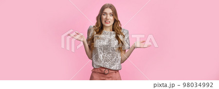 Awkward confused glamour party girl shrugging hands spread sideways dismay grimacing unaware, cannot get clue standing uncertain apologizing accidently bumping car, standing pink background 98034992