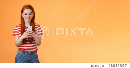 Friendly outgoing modern ginger girl communicating friends, chatting, send funny memes hold smartphone, smiling happy looking gadget display, use social media app enjoy new device feature Friendly outgoing modern ginger girl communicating friends, chatting, send funny memes hold smartphone, smiling happy looking gadget display, use social media app enjoy new device feature 98035367