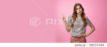 Party sucks boring. Indifferent arrogant snobbish rich glamour young girl sighing sulking displeased disappointed look camra pointing upper left corner unimpressed bored, standing pink background 98035466