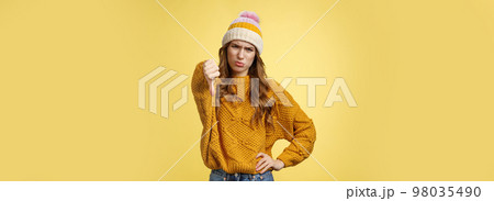 Lame dislike unfollow. Portrait disappointed displeased picky young judgemental woman show thumb-down cringing grimacing unsatisfied expressing disapproval antipathy, yellow background Lame dislike unfollow. Portrait disappointed displeased picky young judgemental woman show thumb-down cringing grimacing unsatisfied expressing disapproval antipathy, yellow background 98035490