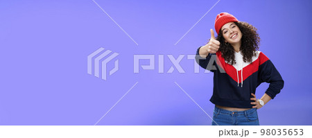 You doing great, like. Portrait of happy delighted young stylish woman in winter beanie and sweatshirt showing thumbs up pleased and satisfied approving and being supportive smiling at camera You doing great, like. Portrait of happy delighted young stylish woman in winter beanie and sweatshirt showing thumbs up pleased and satisfied approving and being supportive smiling at camera 98035653