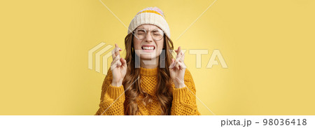 Close-up worried extremely nervous cute nerdy girl college student praying put effort dream come true clench teeth close eyes cross fingers good luck make wish standing supplicating yellow background 98036418