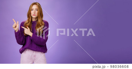 Upset and gloomy woman in sorrow feeling regret of missing huge sales looking reckelss and unhappy pointing questioned at upper left corner with hopeless expression over purple background 98036608