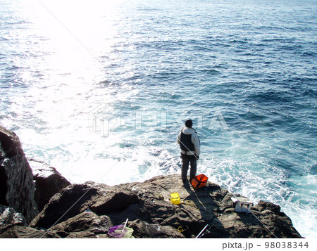 仕掛けを流すウキふかせ釣り中の釣り人の後ろ姿、サラシが大きくはけだしている逆光シルエット画像。 98038344