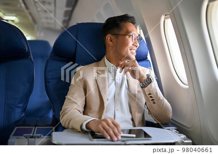 Successful Asian businessman is on his private jet, taking a flight for his business trip. 98040661
