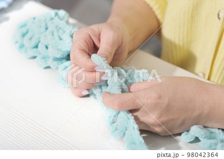 finger knit concept. new way to knit accessories using no needles. hand made knitting. female hands with soft yarn. 98042364