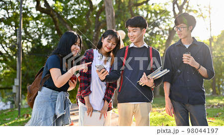 Group of happy Asian college students enjoy talking and walking in the campus's park together. Group of happy Asian college students enjoy talking and walking in the campus's park together. 98044197
