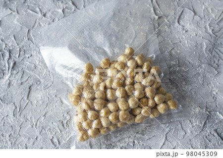 Hazelnuts in a plastic vacuum bag on a gray textured background. Hazelnuts in a plastic vacuum bag on a gray textured background. 98045309