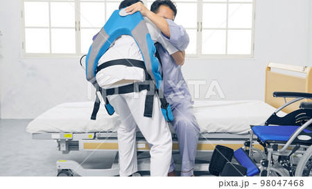 パワーアシストスーツをつけて患者を抱える看護師 移乗介助機器 パワーアシストスーツをつけて患者を抱える看護師 移乗介助機器 98047468