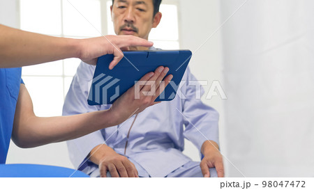 タブレットを見ながら説明を受ける患者 タブレットを見ながら説明を受ける患者 98047472