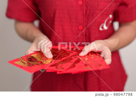 woman holding Chinese red envelope with golden rabbit and blessing word, money gift for happy Lunar New Year holiday. Chinese sentence means happiness, healthy, Lucky and Wealthy woman holding Chinese red envelope with golden rabbit and blessing word, money gift for happy Lunar New Year holiday. Chinese sentence means happiness, healthy, Lucky and Wealthy 98047798