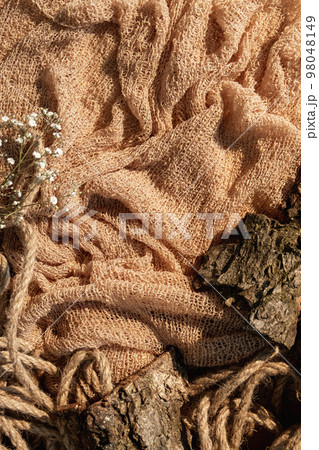 Rustic showcase. Product placement. Nature composition. Cracked brown wood bark pieces twisted rope dried flowers on beige crumpled sack cloth free space decorative background. Rustic showcase. Product placement. Nature composition. Cracked brown wood bark pieces twisted rope dried flowers on beige crumpled sack cloth free space decorative background. 98048149