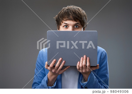 young man hiding his face with laptop young man hiding his face with laptop 98049306