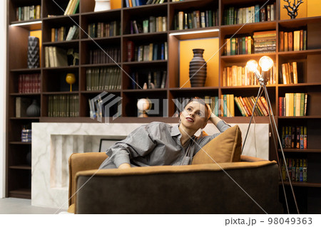 a stylish woman with a short haircut is comfortably seated on a chair at a psychologist's a stylish woman with a short haircut is comfortably seated on a chair at a psychologist's 98049363