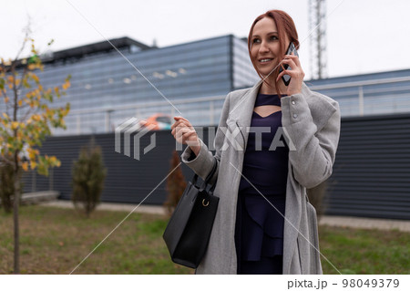Business woman talking on the phone outside the office Business woman talking on the phone outside the office 98049379