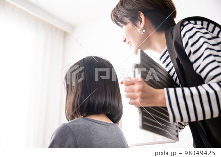 カットの仕上がりを確認する美容師さん 98049425