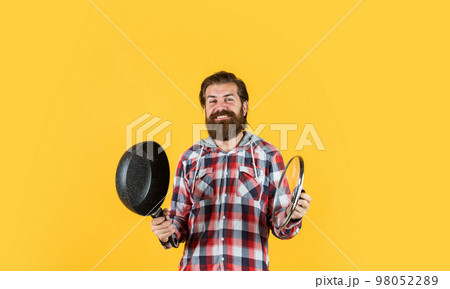 man holding frying pan.. male chef kitchener cooking. hipster checkered shirt for bearded guy cook. unshaven brutal man with kitchen utensil. household goods. friendly shop assistant man holding frying pan.. male chef kitchener cooking. hipster checkered shirt for bearded guy cook. unshaven brutal man with kitchen utensil. household goods. friendly shop assistant 98052289