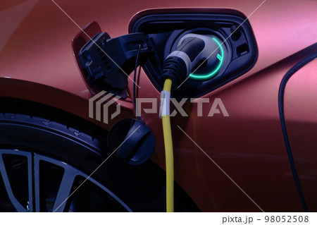 Close-up hand grip plug of industrial electric charging machine connected with socket charge on white electric car for rechargeable battery, zero emission vehicle and green energy for smart life Close-up hand grip plug of industrial electric charging machine connected with socket charge on white electric car for rechargeable battery, zero emission vehicle and green energy for smart life 98052508