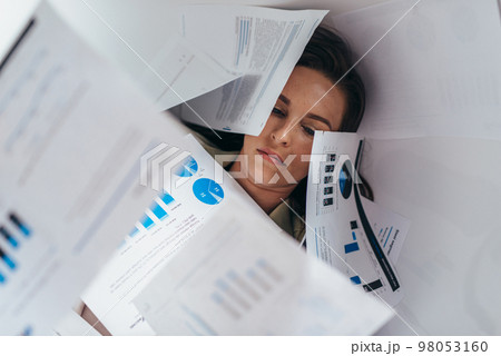 A woman lying covered in papers 98053160