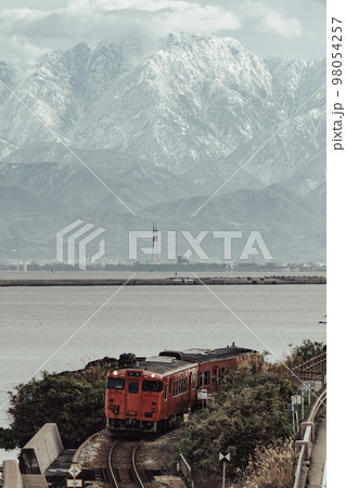 立山連峰と海沿いを走る列車 98054257