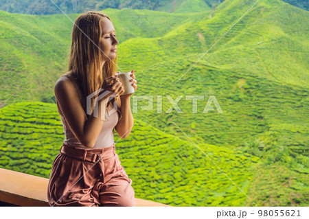 Young woman Drinking Healthy Green Tea against a tea plantation. Healthcare or Herbal medicine concept Young woman Drinking Healthy Green Tea against a tea plantation. Healthcare or Herbal medicine concept 98055621