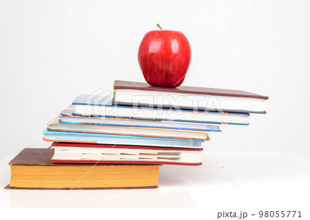 The educational books are stacked in the form of a ladder on the table and with a red juicy apple The educational books are stacked in the form of a ladder on the table and with a red juicy apple 98055771