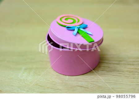 A small pink box with a lid for storing small things is on the table in the apartment 98055796