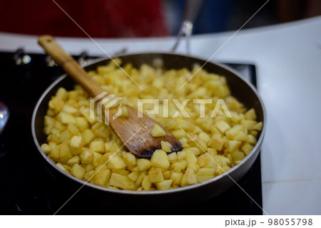 finely chopped apples are fried in sugar on a black frying pan finely chopped apples are fried in sugar on a black frying pan 98055798