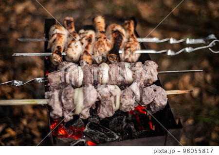 shish kebab, pieces of meat with onion rings on skewers fry in charcoal grills shish kebab, pieces of meat with onion rings on skewers fry in charcoal grills 98055817
