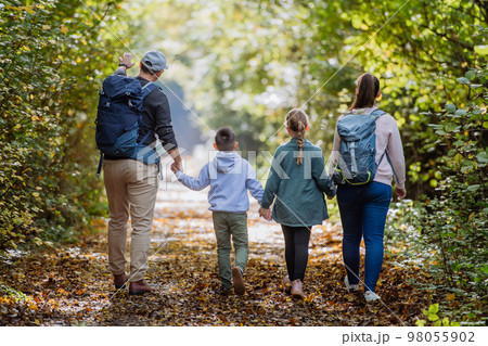 Rear view of family with kids walking in forest. Rear view of family with kids walking in forest. 98055902