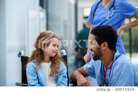 Young multiracial doctor talking with little girl on wheelchair. 98055929