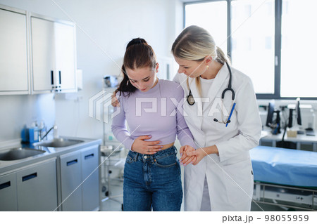 Close-up of doctor helping sick teenage girl in her ambulance office. 98055959