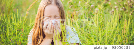 Young woman sneezes because of an allergy to ragweed BANNER, long format Young woman sneezes because of an allergy to ragweed BANNER, long format 98056385
