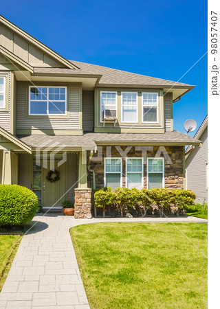 Entrance of family house with concrete pathway over green lawn 98057407