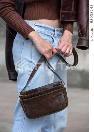close-up photo of small brown leather bag in a woman hands close-up photo of small brown leather bag in a woman hands 98058248