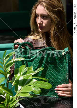 close-up photo of green leather bag in a hands of a beautiful woman close-up photo of green leather bag in a hands of a beautiful woman 98058312
