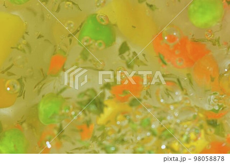 Close-up view of the vegetables with carrots, peas, cauliflower, corn, chopped potatoes and parsley in water background. Texture of boiling soup vegetables. Flat design, top view. Horizontal macro 98058878