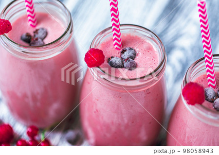 Closeup top view of three milkshakes in glasses jars made from raspberry, blueberries, currant 98058943