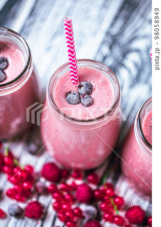 Top view of berries milkshakes in glasses jars made from raspberry, blueberries, currant 98058949