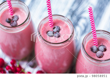 Closeup top view of berries milkshakes in glasses jars made from raspberry, blueberries, currant Closeup top view of berries milkshakes in glasses jars made from raspberry, blueberries, currant 98058951