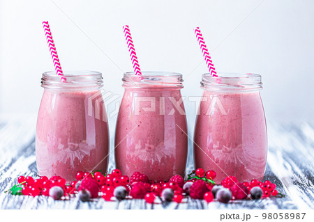 Front view of three jars with yogurt smoothie with cranberry, raspberry, blueberry on wood table Front view of three jars with yogurt smoothie with cranberry, raspberry, blueberry on wood table 98058987