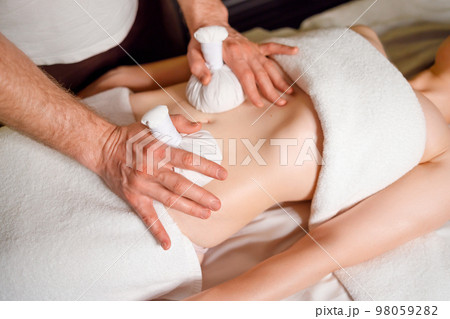 Woman having an abdomen massage with with aromatic herbal bags 98059282