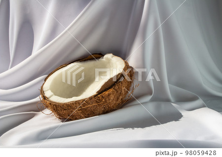 Tropical fruit concept, Halves of fresh white coconut on white fabric background 98059428