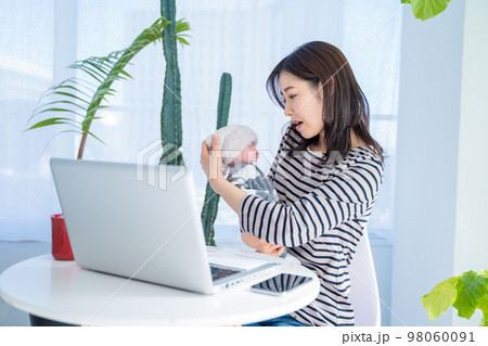 在宅ワークで子供を見ながらビデオチャットする女性 98060091