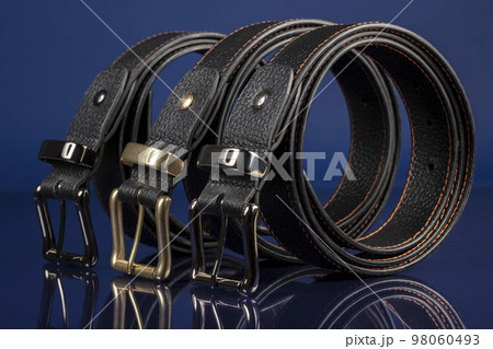 Group of black leather belts on a blue background. Group of black leather belts on a blue background. 98060493