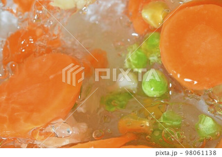 Close-up fresh soup vegetables with carrots, peas, cauliflower and corn on white background. Soup vegetables with carrots, peas, cauliflower and corn in boiling water on white background, close-up. Close-up fresh soup vegetables with carrots, peas, cauliflower and corn on white background. Soup vegetables with carrots, peas, cauliflower and corn in boiling water on white background, close-up. 98061138