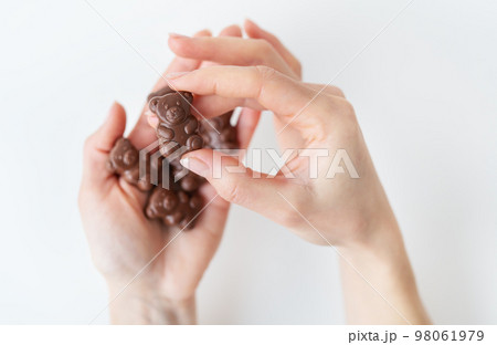 The girl holds a chocolate teddy bear in her hands on a white background. Charming chocolate and delicious gift. 98061979