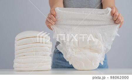 A woman chooses an adult diaper from a pile. Urinary incontinence problem. 98062000