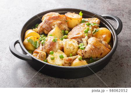Chicken pieces with potato wedges and roasted in a lemon garlic white wine sauce close-up in a frying pan. Horizontal Chicken pieces with potato wedges and roasted in a lemon garlic white wine sauce close-up in a frying pan. Horizontal 98062052