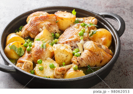 Chicken Vesuvio is pan-seared and baked chicken, potatoes, and peas with a ridiculously delicious herbed wine sauce close-up in a frying pan. Horizontal 98062053